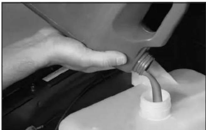 Close-up of a hand pouring liquid from a fuel can into a plastic bottle (no visible text or symbols)