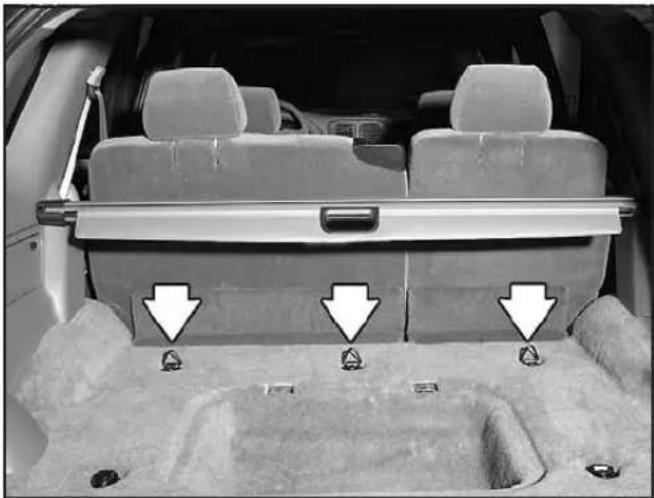 Interior view of a car showing rear seats and seatbelt structure with three white arrows pointing to the backrest area (no text or symbols visible)