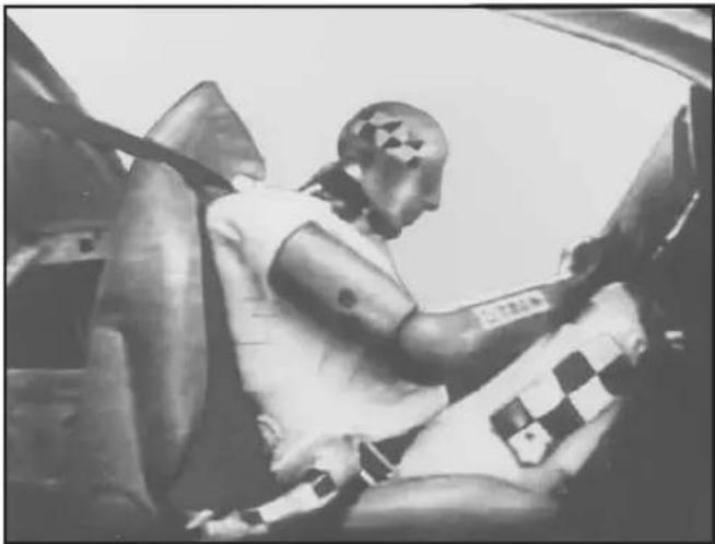 Black-and-white photo of a person wearing a beret and a checkered shirt, seated in a car (no visible text or symbols)