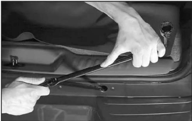 Close-up of hands using a tool to adjust or install a car engine compartment (no visible text or symbols)