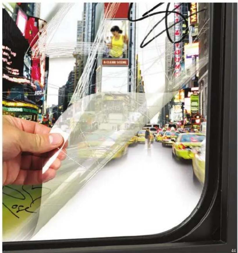 Street photo with visible store signboards and a hand holding a transparent plastic film, showing urban traffic scene.