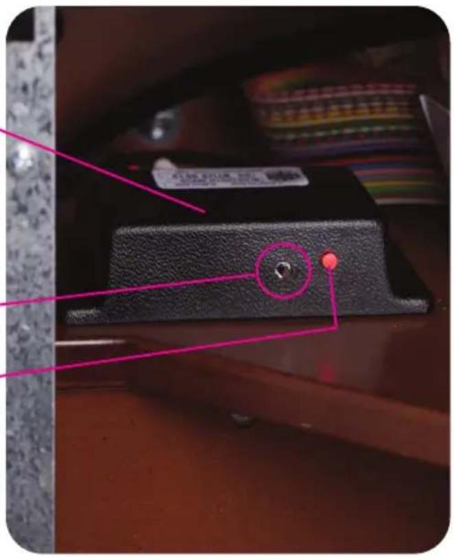 Close-up photo of a black electronic device with a pink annotation highlighting a circular feature and a red dot, likely indicating a measurement or inspection point.