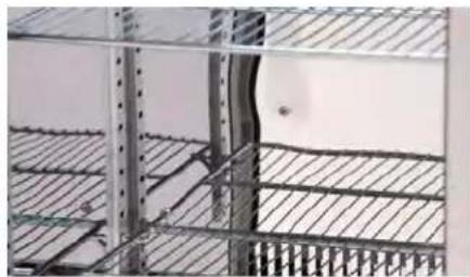 Interior view of a metal shelving unit with grid patterns and a small room in the background (no visible text or symbols)