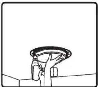 Simple line drawing of a hand holding a circular object above a wall (no text or symbols)