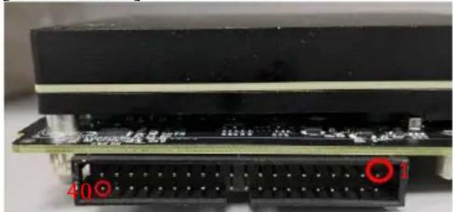 Close-up of electronic components including a black rectangular board and a breadboard with red circular markers (no readable text or symbols)