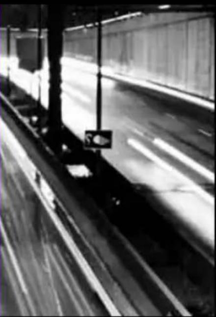 Black and white photo of a highway with visible lane markings and overpass structure (no text or symbols)
