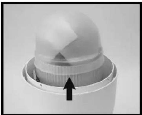 Close-up of a white plastic container with a lid and internal structure, showing an upward arrow (no text or symbols visible)