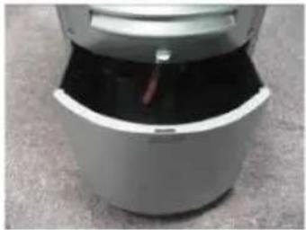 Close-up of a white cylindrical device with a red handle, placed on a textured surface (no visible text or symbols)