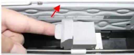 Close-up of a hand pressing down on a white plastic component with a red arrow pointing to it (no text or symbols visible)