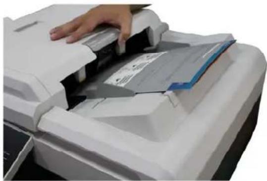 Close-up of a hand using a white scanner to press or download a document (no visible text or symbols)