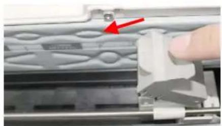 Close-up of a hand operating a mechanical component with a red arrow pointing to a small component (no visible text or symbols)