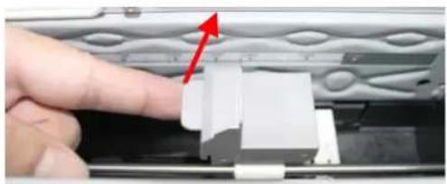 Close-up of a finger pressing down on a white plastic component with a red arrow indicating the motion (no text or symbols visible)