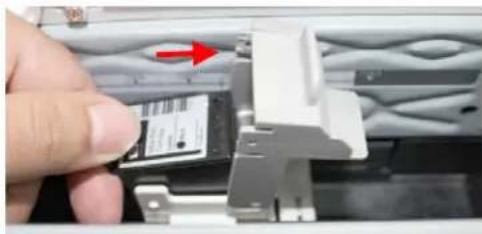 Close-up of a hand inserting a small electronic component into a wall, with a red arrow indicating direction (no visible text or symbols)