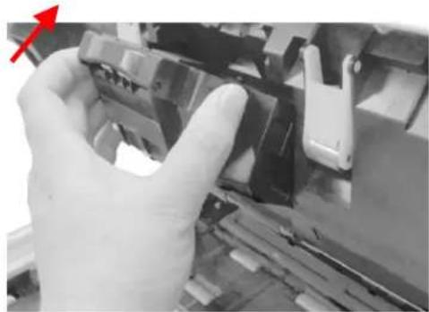 Close-up of a hand holding a mechanical component, with a red arrow pointing to the left (no visible text or symbols)