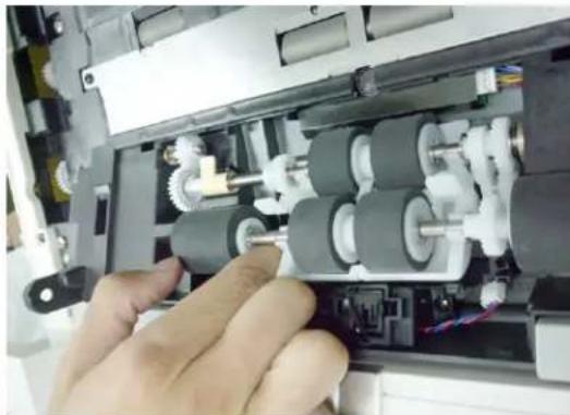 Close-up of hands operating a mechanical assembly with gears and shafts (no visible text or symbols)