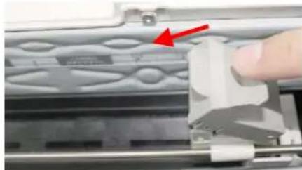 Close-up of a hand using a 3D printer to adjust a component on a metal frame (no visible text or symbols)