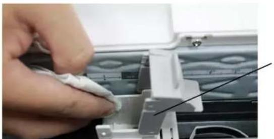Close-up of a hand holding a small white object, next to a mechanical component with no visible text or symbols.