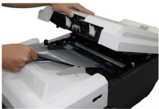 Person operating a printer with open lid and paper roll (no visible text or symbols)