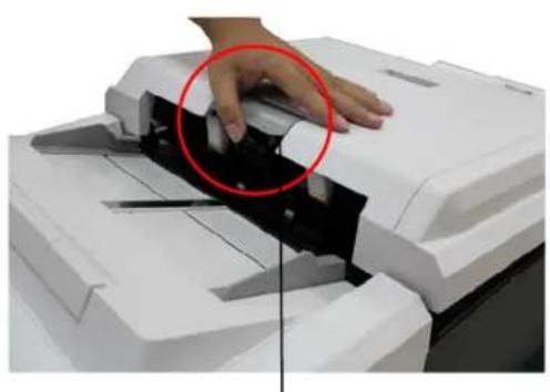 Close-up of a hand operating a printer with a black cover and a red circle highlighting the part (no visible text or symbols)