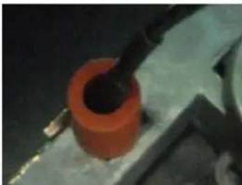 Close-up of a mechanical component with orange cylindrical body and black shaft (no visible text or symbols)