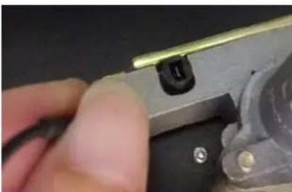 Close-up of a hand holding a metal tool with a small black component, no visible text or symbols