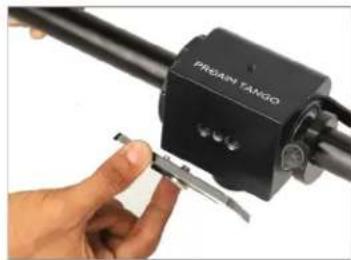 Close-up of a hand holding a black TANGIO sensor device with a tool, no visible text or symbols on the device itself.