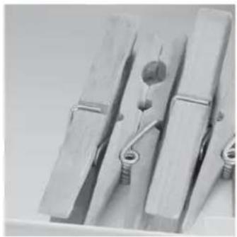 Close-up of three wooden clothespins with metal clips, no text or symbols visible