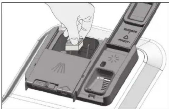 Een hand steekt een klein onderdeel in een apparaatbehuizing (geen zichtbare tekst of symbolen)