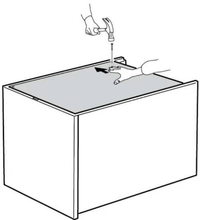 Line drawing of a hand using a hammer to press or install a component into a rectangular box (no text or symbols)