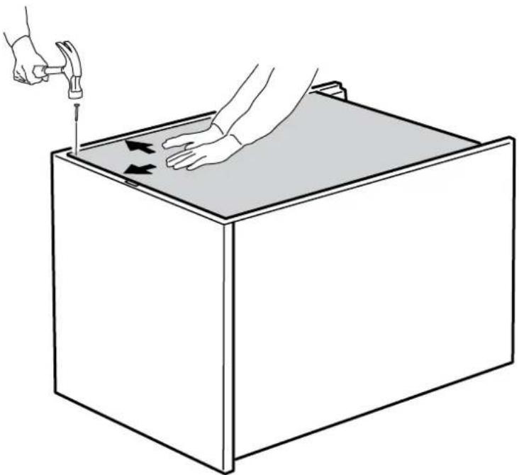 Line drawing of hands using a hammer to press down a rectangular box with arrows indicating motion (no text or symbols)