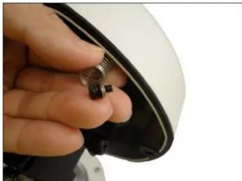 Close-up of a hand holding a small metallic connector into a white helmet (no text or symbols visible)
