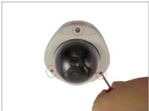Close-up of a surveillance camera with a screwdriver inserted, showing no text or symbols on the device itself.
