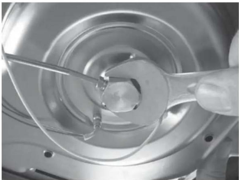 Close-up of a hand holding a wrench inside a metallic mechanical component (no visible text or symbols)