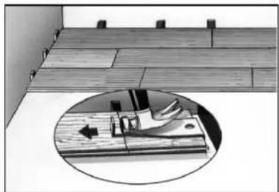 Interior view of a tiled room with wooden flooring and a circular inset showing a hand pressing a work on a wooden surface (no text or symbols)