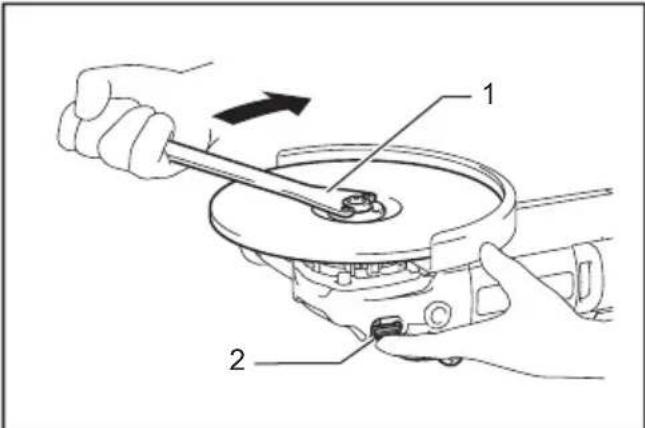 Technical diagram showing a hand operating a mechanical device with labeled parts 1 and 2, indicating a turning or disassembly process.