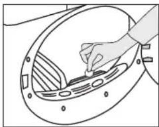 Line drawing of a hand placing a component into a circular device with a gridded panel (no text or symbols).