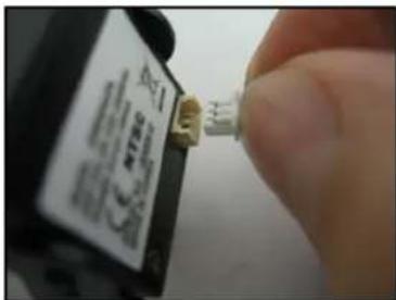 Close-up of a hand holding a small electronic component with visible text labels and symbols