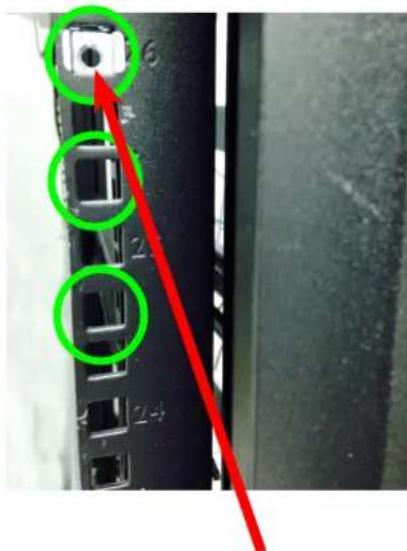 Close-up of a server rack with labeled ports and a red arrow pointing to a port, highlighting green circular features.