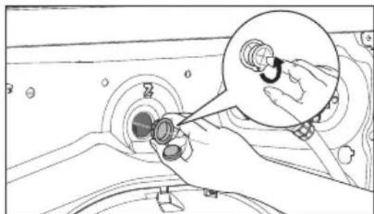 Line drawing of a hand holding a small mechanical component, with an inset showing a hand adjusting a circular component.