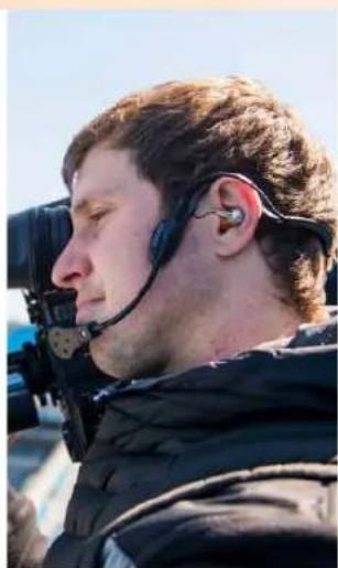 Profile view of a person wearing a headset and jacket, outdoors under clear sky (no visible text or symbols)