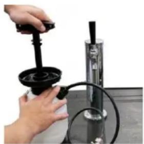 Close-up of a hand using a mechanical device to measure a black cylindrical component with a bulb, mounted on a metal stand (no visible text or symbols)