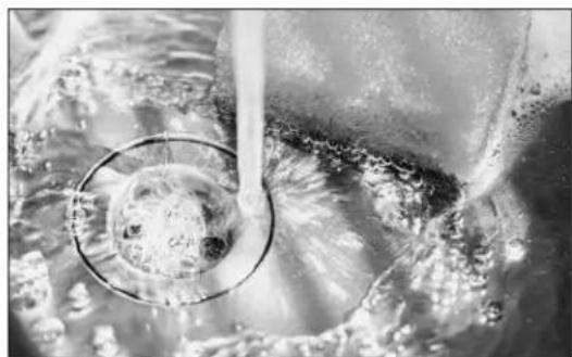 Close-up of a pipe passing through a container with bubbles rising, showing fluid and bubbles (no text or symbols visible)