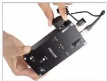 Close-up of hands assembling a black electronic device labeled 'Firebox' with wires and connectors (no readable text beyond label)