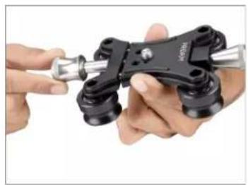 Close-up of hands holding a mechanical clamp or bracket with a metallic tool (no visible text or symbols)