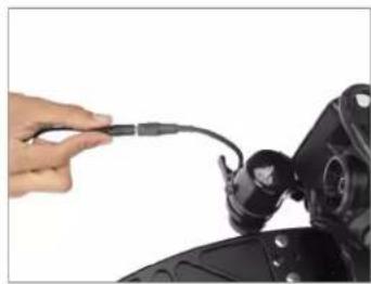 Close-up of a hand connecting a cable to a mechanical component (no visible text or symbols)