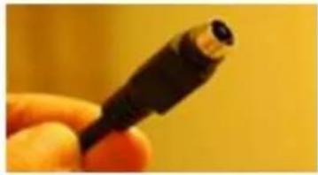 Close-up of a hand holding a black USB connector against a yellow background (no text or symbols visible)