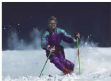 Skier in purple and teal suit skiing down a snowy slope at night (no visible text or symbols)