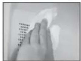 Hand holding a cloth with printed text in Chinese characters, likely from a document or book.