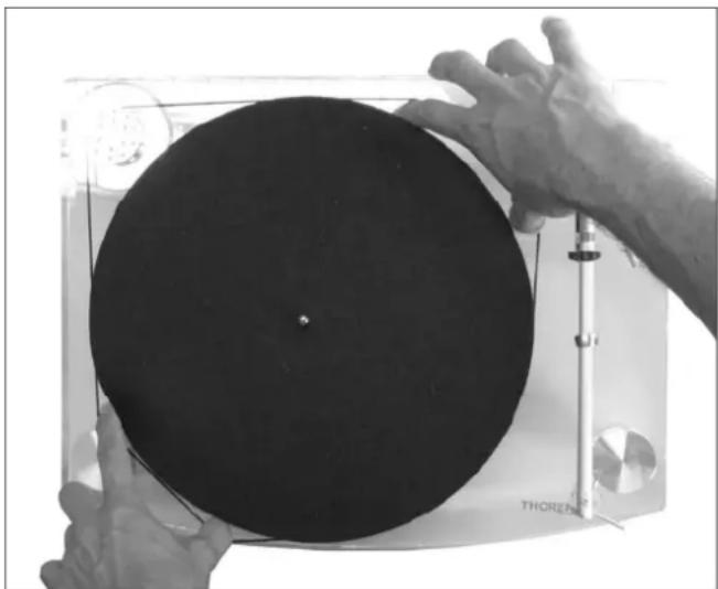 Close-up of hands operating a circular disc on a CD or DVD stand (no visible text or symbols)