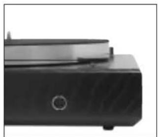 Close-up of a black electronic device with a circular button and lid (no visible text or symbols)